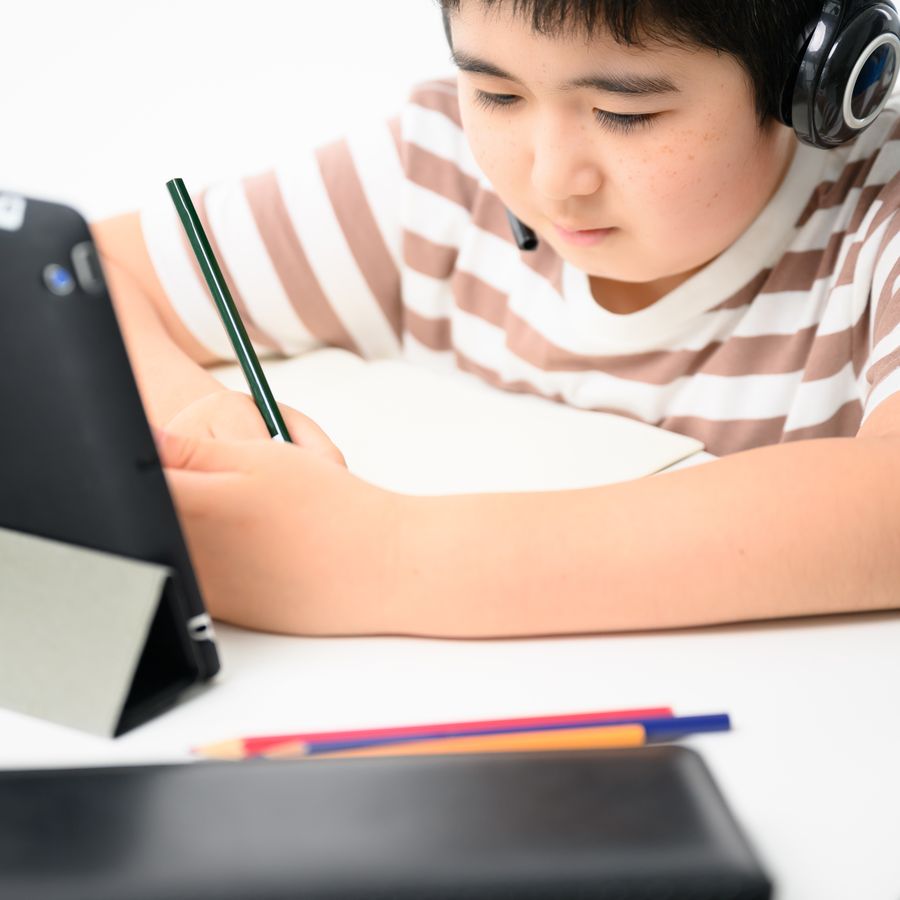 ヘッドホンをつけてタブレットで学ぶ子ども